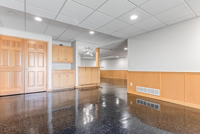 spare room featuring a wainscoted wall, visible vents, and a drop ceiling