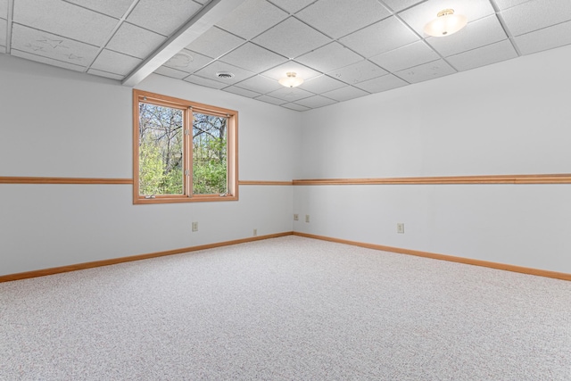 spare room featuring carpet, baseboards, and a drop ceiling