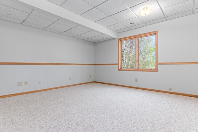 empty room with a paneled ceiling, baseboards, and carpet
