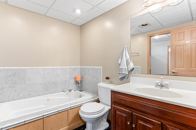 bathroom featuring toilet, a drop ceiling, vanity, and a bath