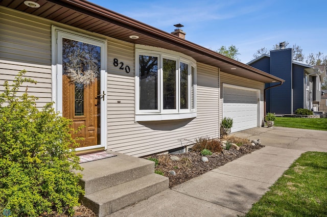 doorway to property with driveway, a garage, and a chimney