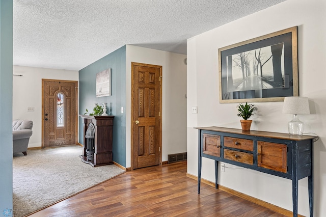 foyer with wood finished floors, a textured ceiling, and baseboards