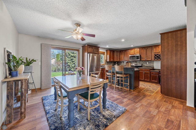 dining space featuring ceiling fan, light wood-style floors, a textured ceiling, and recessed lighting