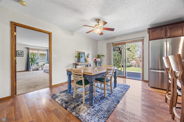dining space with ceiling fan, light wood finished floors, a textured ceiling, and baseboards