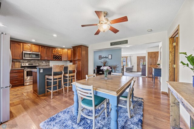 dining room with light wood finished floors, ceiling fan, a textured ceiling, and recessed lighting