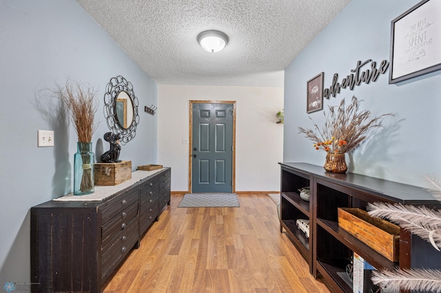 entrance foyer featuring a textured ceiling, light wood-style floors, and baseboards