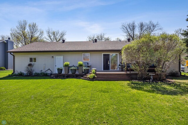 back of property featuring a yard, a chimney, a wooden deck, and a shingled roof