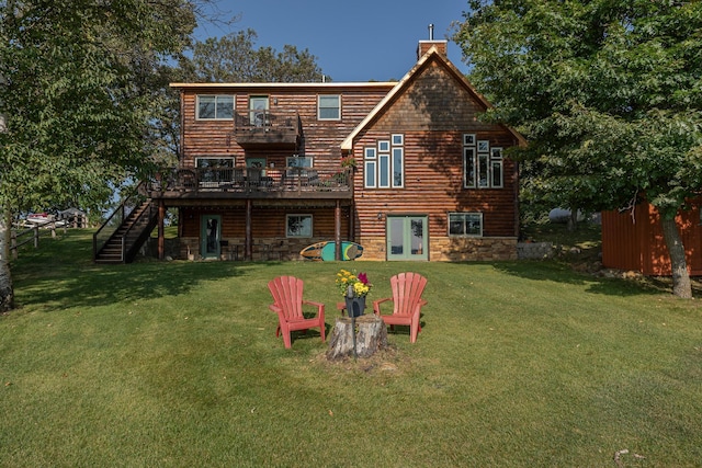 back of property with stairs, a chimney, a deck, and a lawn