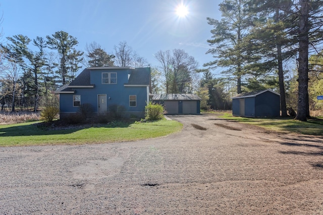 exterior space featuring a front yard, an outdoor structure, a storage unit, and a detached garage