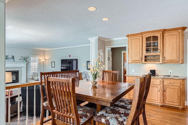 1237 Summit Oaks Dr, Burnsville, MN 55337 - dining space featuring a textured ceiling, crown molding, a premium fireplace, light wood-style floors, and recessed lighting