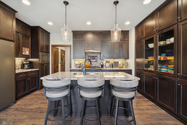 kitchen featuring stainless steel appliances, dark brown cabinets, dark wood-style flooring, backsplash, and recessed lighting
