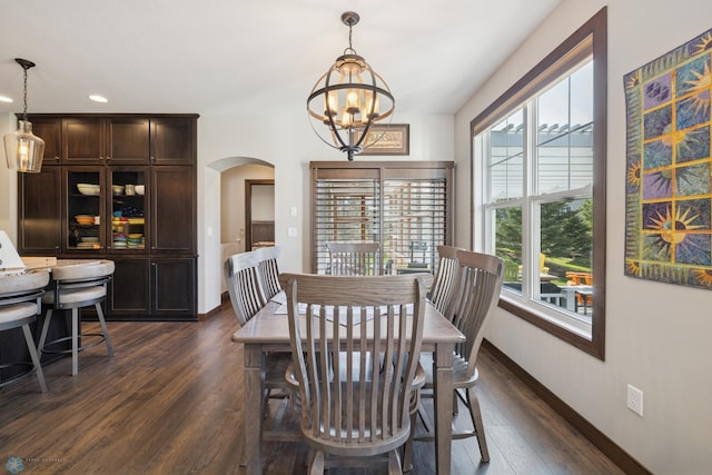 dining room with arched walkways, a chandelier, dark wood-type flooring, baseboards, and recessed lighting