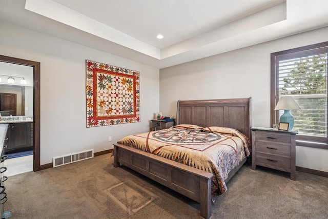 carpeted bedroom featuring baseboards, recessed lighting, ensuite bathroom, and a raised ceiling