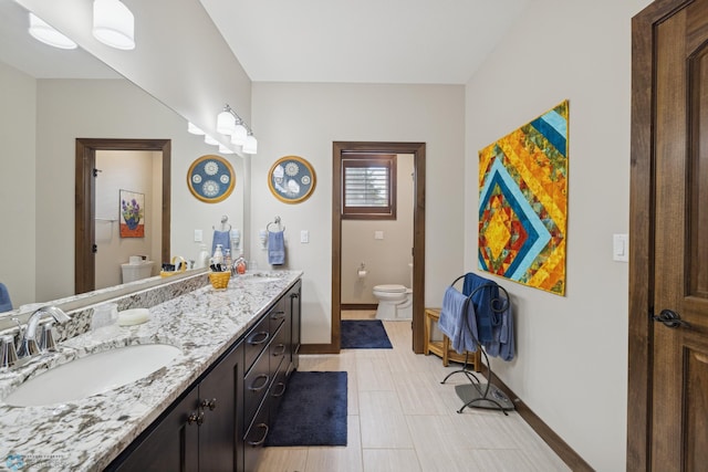 bathroom featuring toilet, baseboards, and double vanity