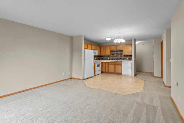 610 Whiskey Rd NW Unit 115, Isanti, MN 55040 - kitchen with white appliances, light countertops, light colored carpet, decorative backsplash, and a chandelier