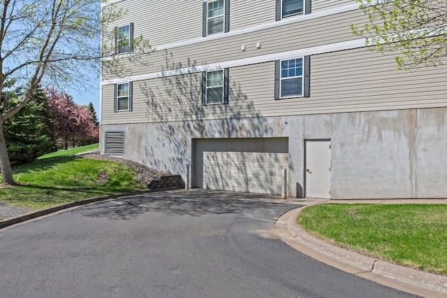 610 Whiskey Rd NW Unit 115, Isanti, MN 55040 - view of side of property featuring asphalt driveway, a garage, and a yard