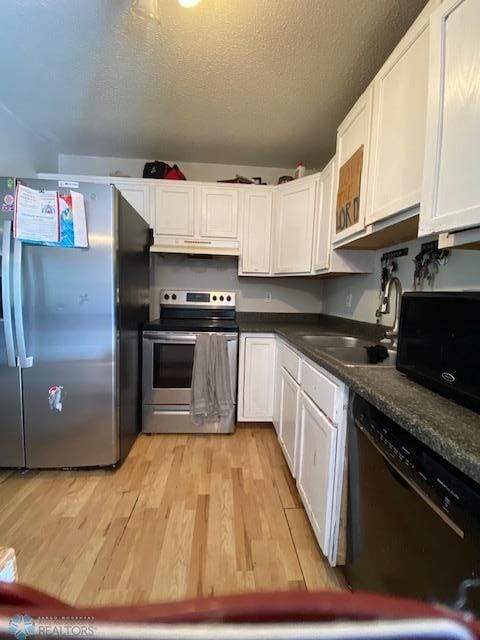 kitchen with black appliances, under cabinet range hood, light wood-style floors, white cabinetry, and dark countertops