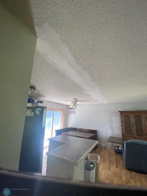 playroom with a textured ceiling, ceiling fan, wood finished floors, and a baseboard radiator