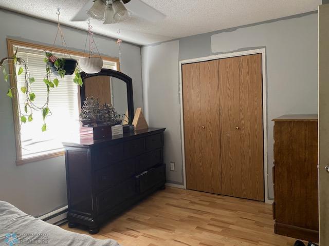 bedroom featuring light wood-style floors, a textured ceiling, and a closet