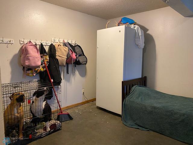 bedroom featuring concrete floors and freestanding refrigerator
