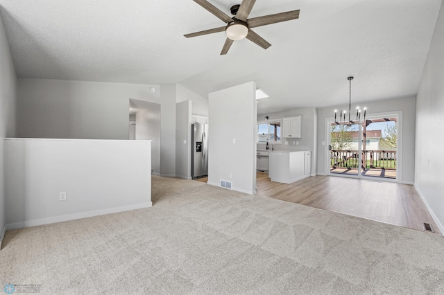 1683 Oakwood Dr, West Fargo, ND 58078 - unfurnished living room with light carpet, a chandelier, ceiling fan, baseboards, and vaulted ceiling