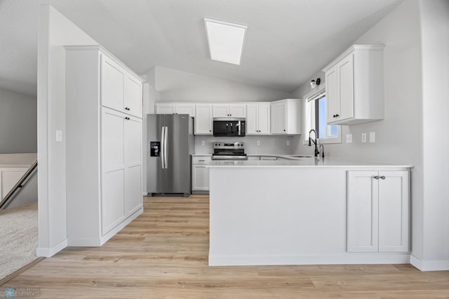 1683 Oakwood Dr, West Fargo, ND 58078 - kitchen featuring appliances with stainless steel finishes, a peninsula, vaulted ceiling, white cabinetry, and light countertops