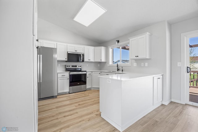 1683 Oakwood Dr, West Fargo, ND 58078 - kitchen featuring appliances with stainless steel finishes, light wood finished floors, a peninsula, a sink, and lofted ceiling