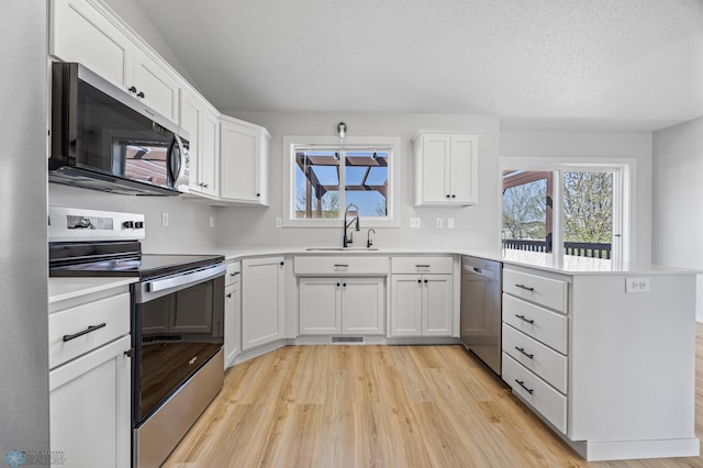 1683 Oakwood Dr, West Fargo, ND 58078 - kitchen with appliances with stainless steel finishes, a sink, a peninsula, light wood-style flooring, and white cabinets