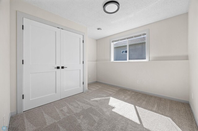 1683 Oakwood Dr, West Fargo, ND 58078 - unfurnished bedroom with carpet flooring, a textured ceiling, a closet, and baseboards