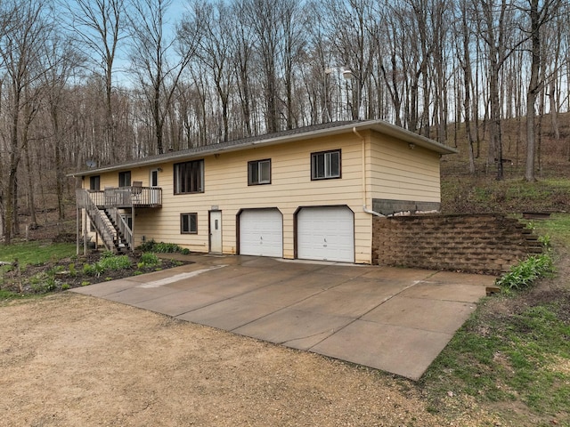 view of front facade with stairway, a wooden deck, a garage, and driveway