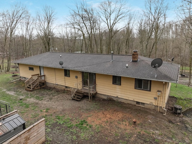 rear view of property featuring a chimney and roof with shingles