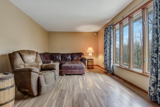 living room with light wood-type flooring, baseboards, and a healthy amount of sunlight