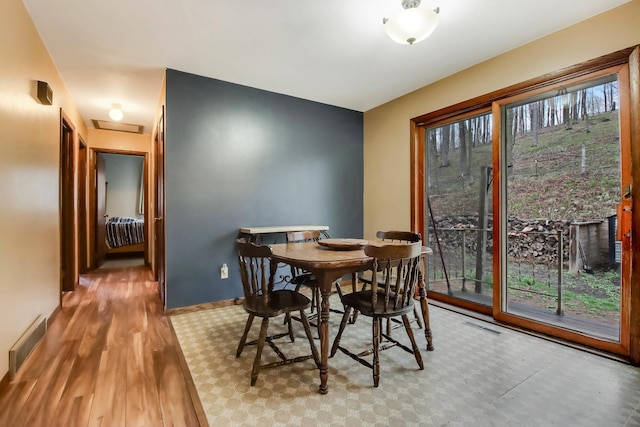 dining room featuring baseboards, attic access, visible vents, and wood finished floors