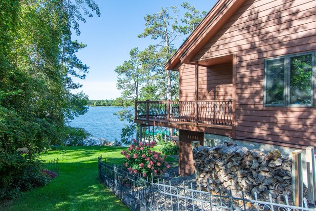 view of property exterior with a water view, fence, and a lawn
