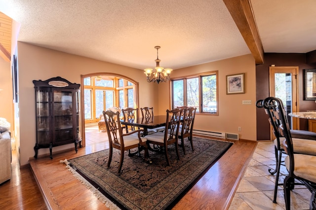 dining space featuring light wood finished floors, an inviting chandelier, a textured ceiling, and a healthy amount of sunlight