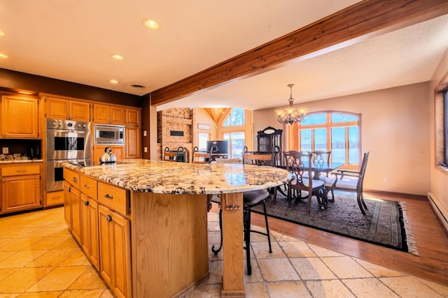 kitchen with a kitchen bar, a notable chandelier, appliances with stainless steel finishes, light stone counters, and recessed lighting