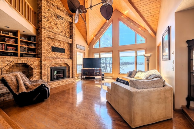 living area featuring baseboard heating, wooden ceiling, a brick fireplace, high vaulted ceiling, and wood finished floors