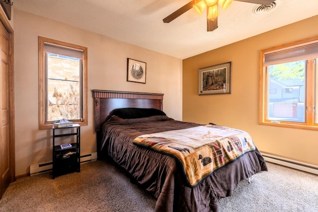 carpeted bedroom with multiple windows, a ceiling fan, visible vents, and baseboard heating