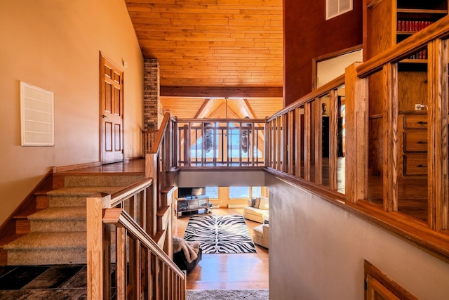 stairway featuring wood ceiling, visible vents, wood finished floors, and high vaulted ceiling