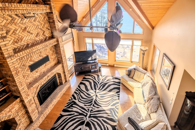 living area with wood ceiling, wood finished floors, high vaulted ceiling, a brick fireplace, and a baseboard radiator