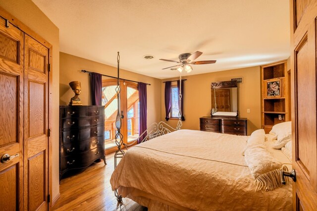bedroom with a ceiling fan, visible vents, wood finished floors, and access to exterior