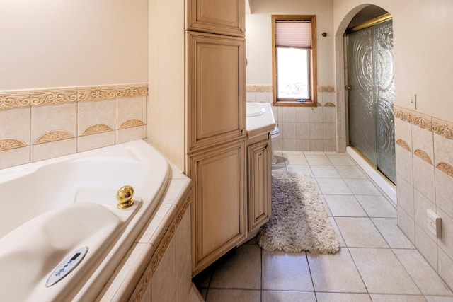 full bathroom with tile patterned floors, tile walls, a bath, a shower stall, and wainscoting