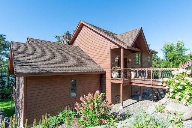 rear view of house with a chimney, stairway, and a deck