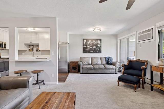 living room featuring carpet, ceiling fan, a wall mounted air conditioner, a textured ceiling, and baseboards