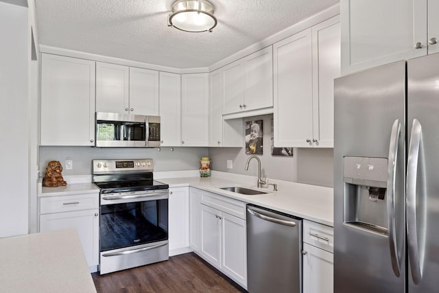kitchen with stainless steel appliances, a sink, light countertops, white cabinetry, and a textured ceiling