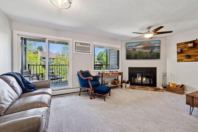 living area featuring carpet flooring, plenty of natural light, a ceiling fan, a glass covered fireplace, and a textured ceiling