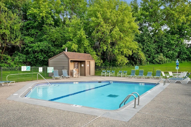 community pool featuring fence, view of scattered trees, and a patio