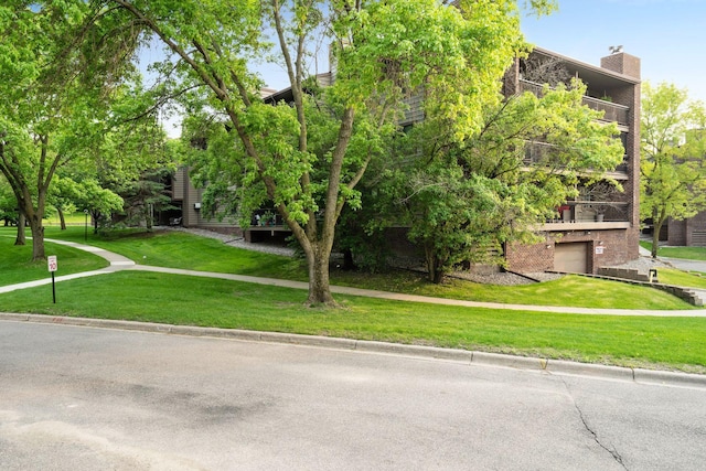 view of property's community with an attached garage and a lawn