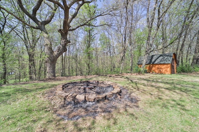 24997 145th Ave, Fort Ripley, MN 56449 - view of green lawn with an outdoor fire pit, a storage unit, an outbuilding, and a view of trees