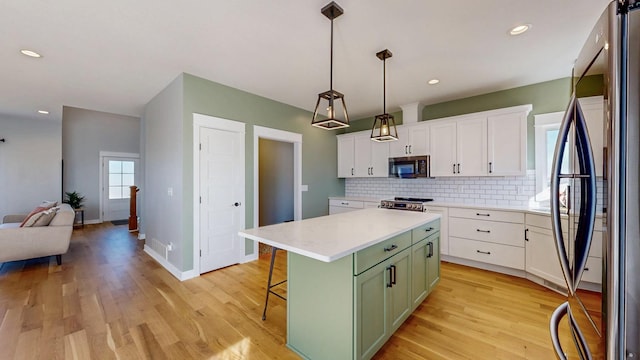 577 Keefe Ct NW, Eyota, MN 55934 - kitchen with appliances with stainless steel finishes, green cabinets, white cabinetry, light countertops, and a center island
